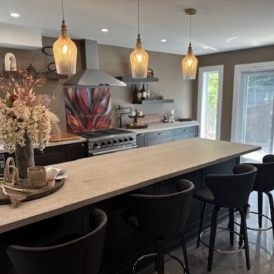 Kitchen island with bar stools under three glass pendant lights